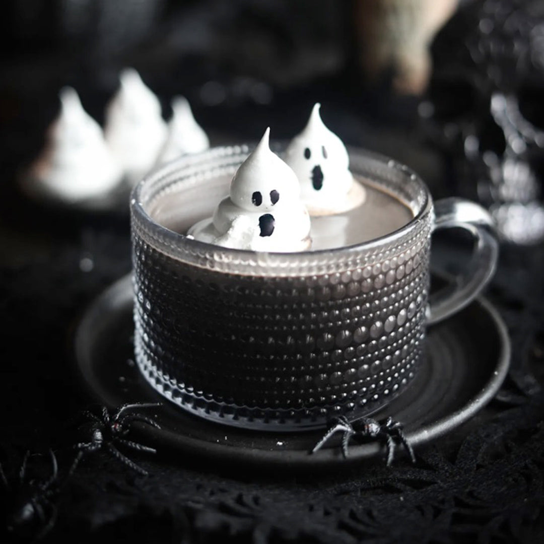 Cup of dark hot chocolate with ghost-shaped marshmallows on a dark background
