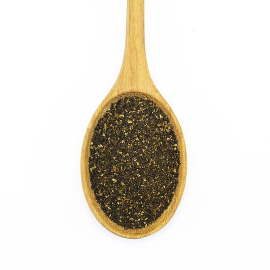 A wooden spoon filled with Dark Chili Powder, photographed from above on a white background.