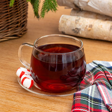 Chocolate Peppermint Black Tea in Glass Mug next to candy cane pieces and flannel