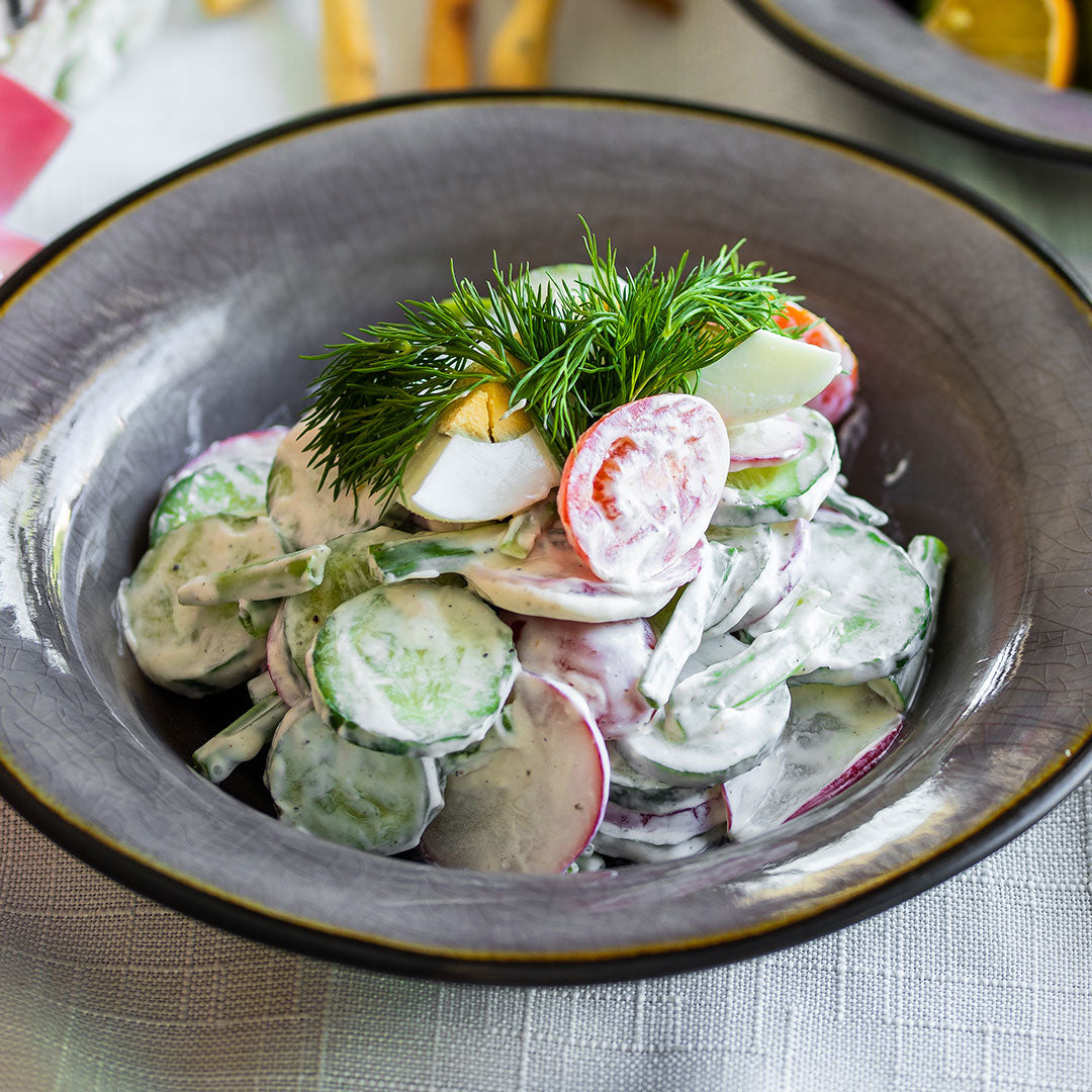 Creamy cucumber and radish salad with dill tomatoes and hard boiled eggs on top