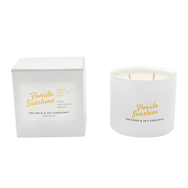 The Florida Sunshine Candle from The Spice & Tea Exchange is a white soy jar candle with two wicks. Both the candle and its box are labeled, featuring a citrusy scent with notes of white tea and rose.