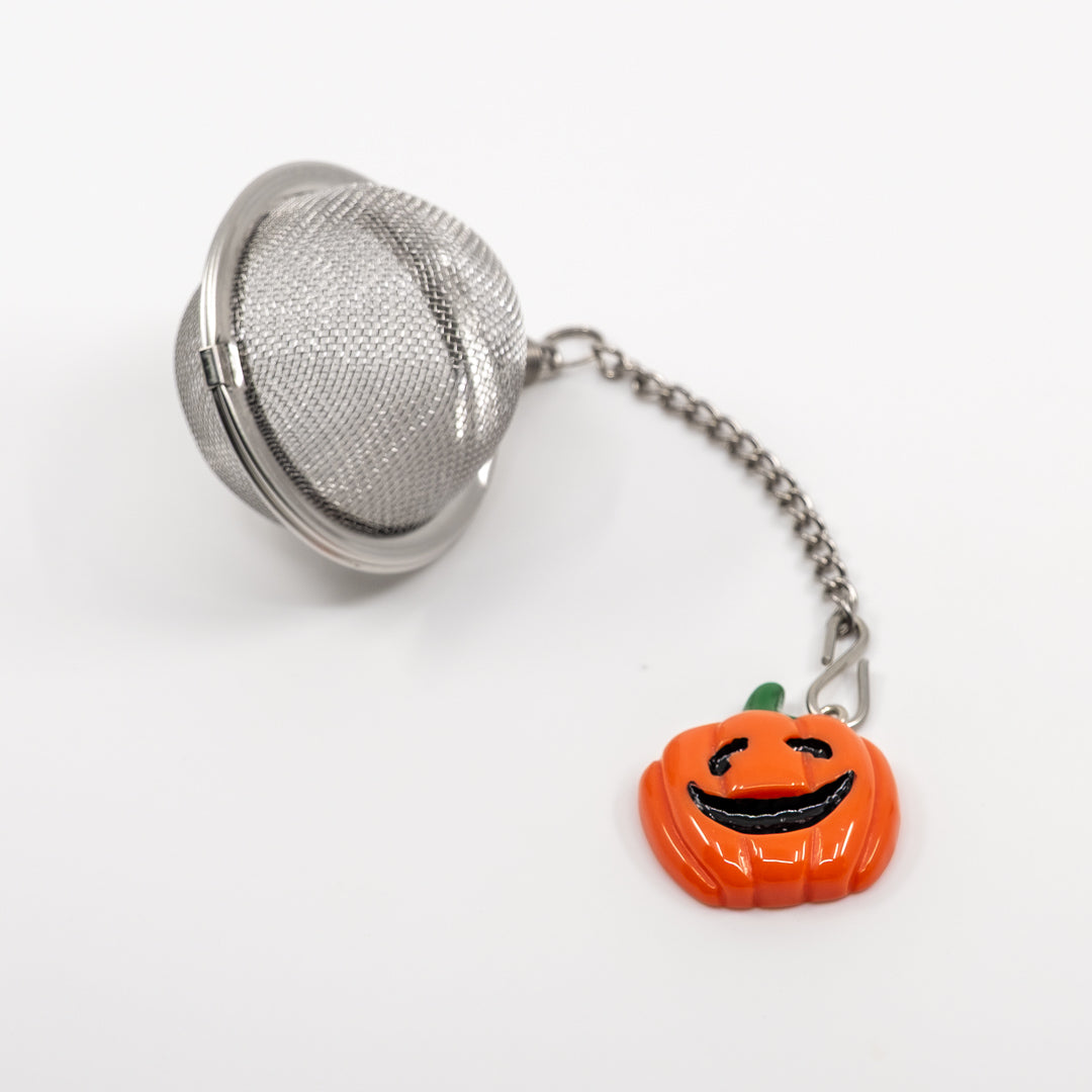 Tea ball with a pumpkin charm on a white background