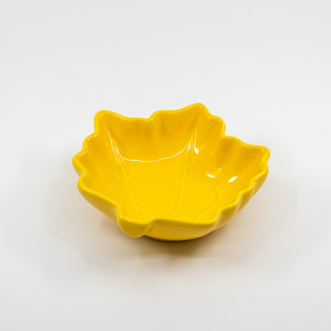 Yellow ceramic leaf bowl with wavy edge on a white background