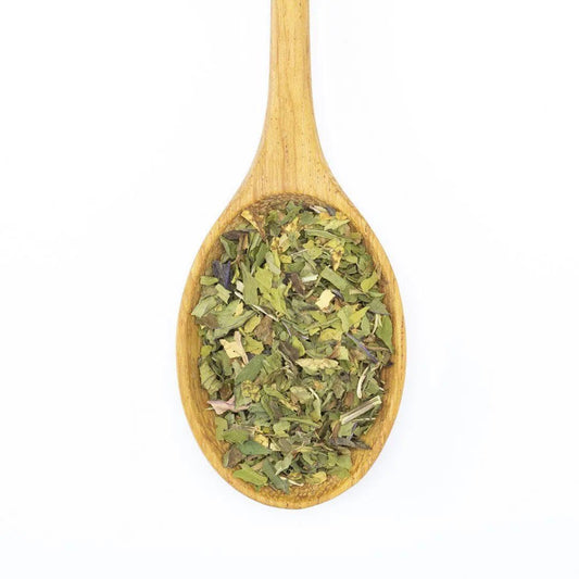 A wooden spoon filled with Organic Peppermint and other dried green herbs, photographed on a white background.