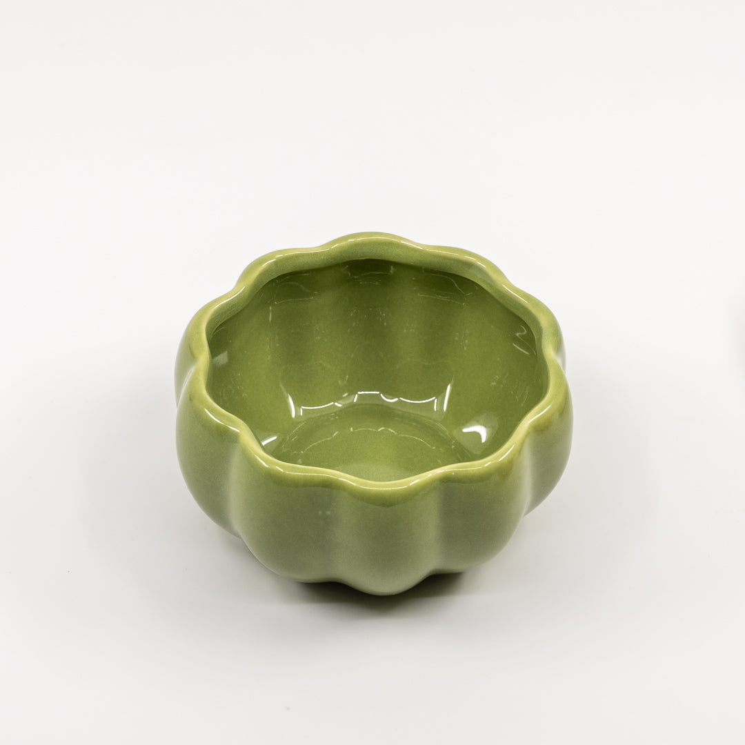 Green ceramic pumpkin bowl on a white background
