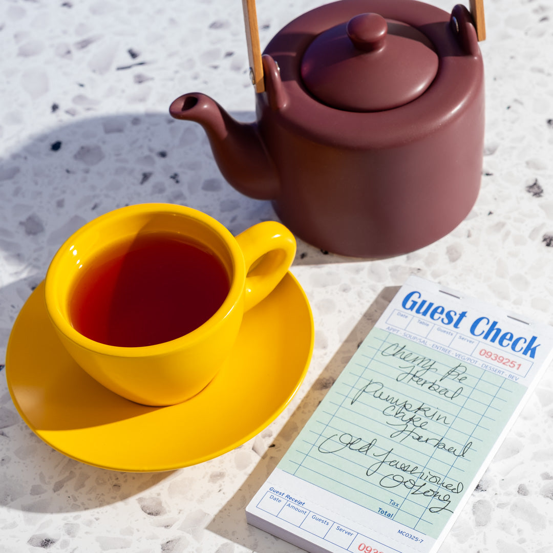 Pumpkin Cake Herbal Tea in yellow mug next to plum teapot