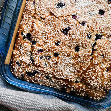 Baked good with Swedish pearl sugar on top and blueberries in a blue container