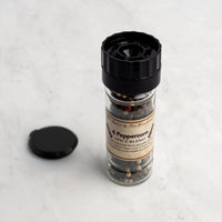 4 Peppercorn spice blend bottle with black lid on a light gray background