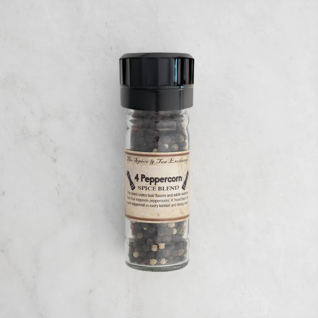 4 Peppercorn spice blend in a glass jar with a black lid on a light gray background