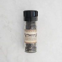 4 Peppercorn spice blend in a glass jar with a black lid on a light gray background