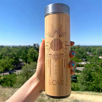 Wooden tumbler with geometric design and 'LOVE' text held against a scenic background