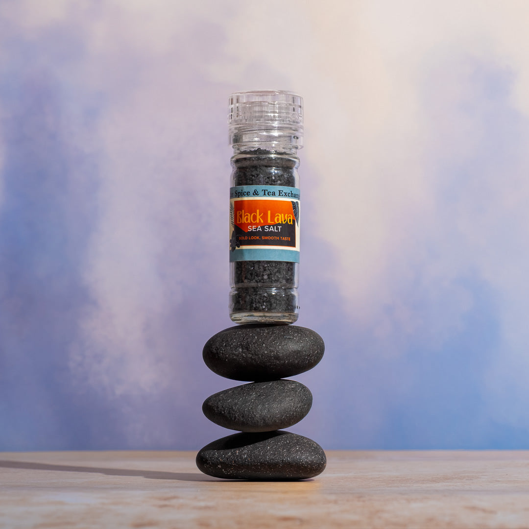 Black Lava sea salt grinder on stacked stones with a blurred background.