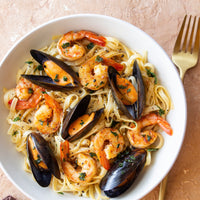  bowl of pasta with shrimp and mussels on a beige background