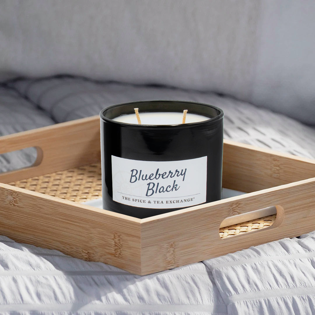 Candle labeled 'Blueberry Black' on a wooden tray with a blurred background