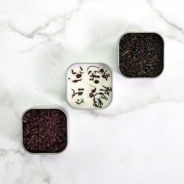 Three small square containers with tea leaves on a marble surface