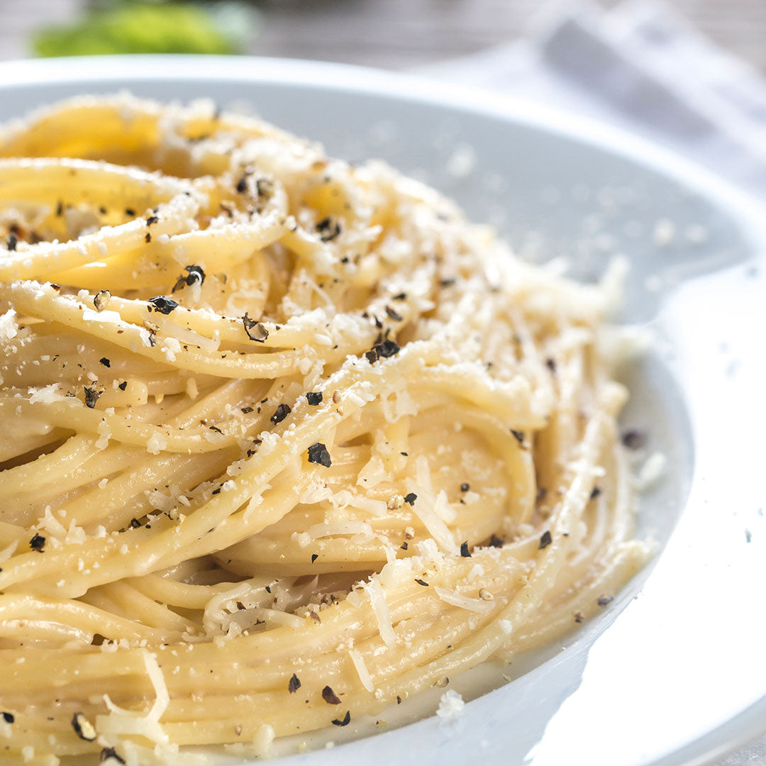 Spaghetti dish with pepper and cheese on a white plate