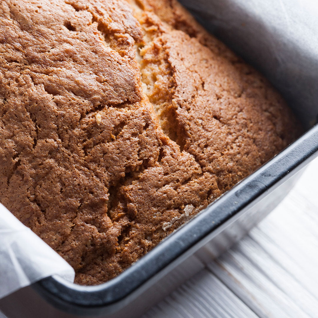 Loaf of bread in a baking pan on a white background