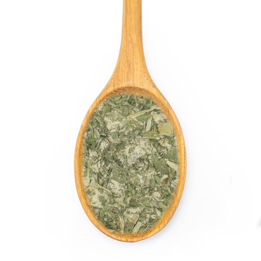 A wooden spoon filled with dried green leafy herbs, shown against a plain white background.