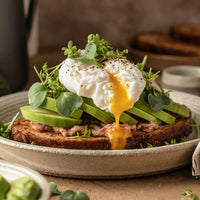 Poached egg on avocado slices and toast covered in seasoning