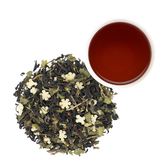 Chocolate Peppermint Black Tea loose leaf with white snowflakes next to white mug of brewed tea