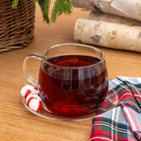 Chocolate Peppermint Black Tea in Glass Mug next to candy cane pieces and flannel