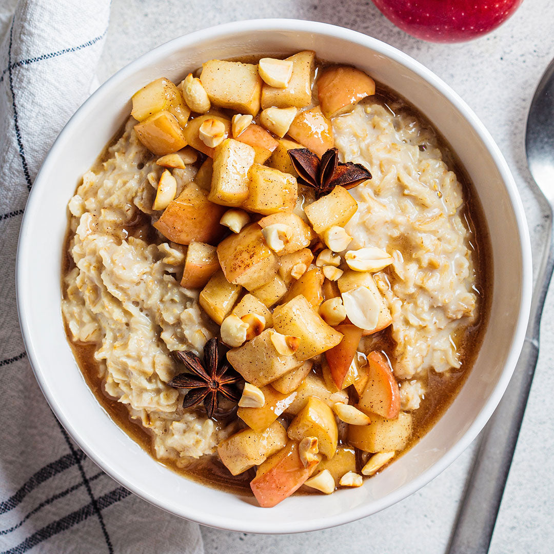 Bowl of oatmeal with apples and nuts on a light background
