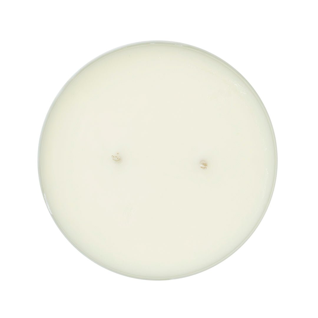 Top-down view of a round, single-wick candle with creamy off-white wax on a solid white background.