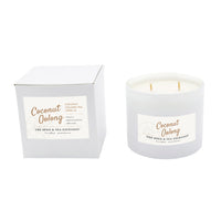 A coconut oolong scented candle in a frosted white glass jar next to its white cardboard packaging box, both featuring a white label with gold text from The Spice & Tea Exchange.