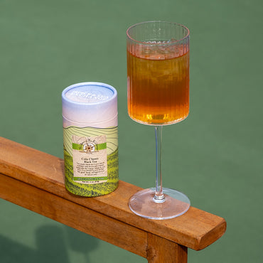 Tea canister and glass of tea on a wooden surface with a green background