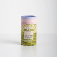 Cola Classic Black Tea in decorative paper tube on white background.
