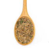 A wooden spoon filled with a textured herb and spice blend, shown against a solid white background.