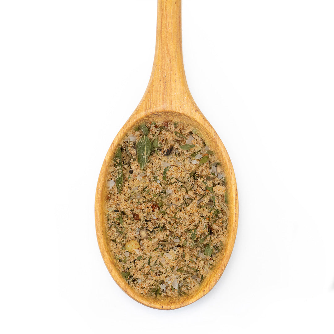 A wooden spoon filled with a textured herb and spice blend, shown against a solid white background.