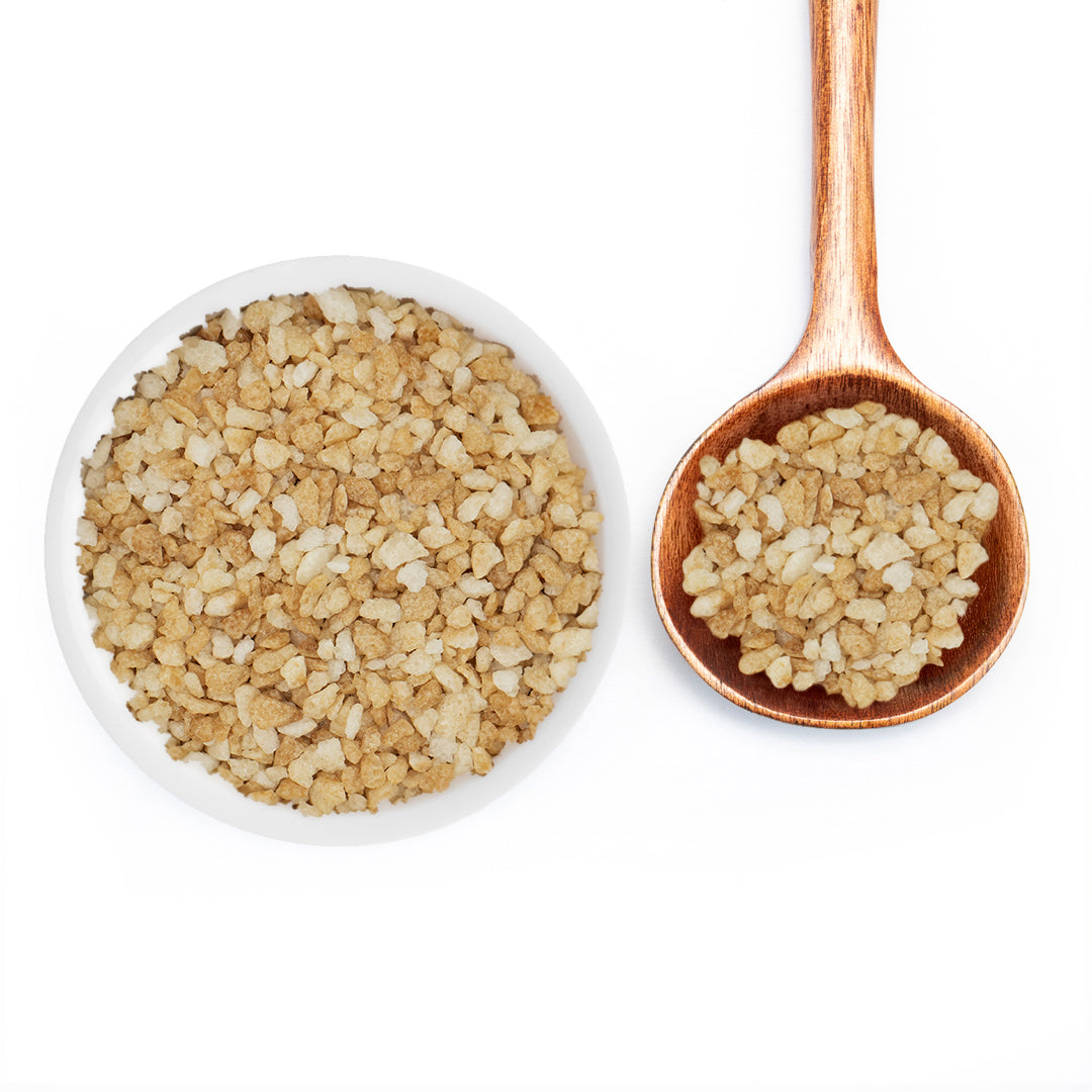 A top-down view of a white bowl and a wooden spoon filled with coarse, vanilla sugar on a plain white background.