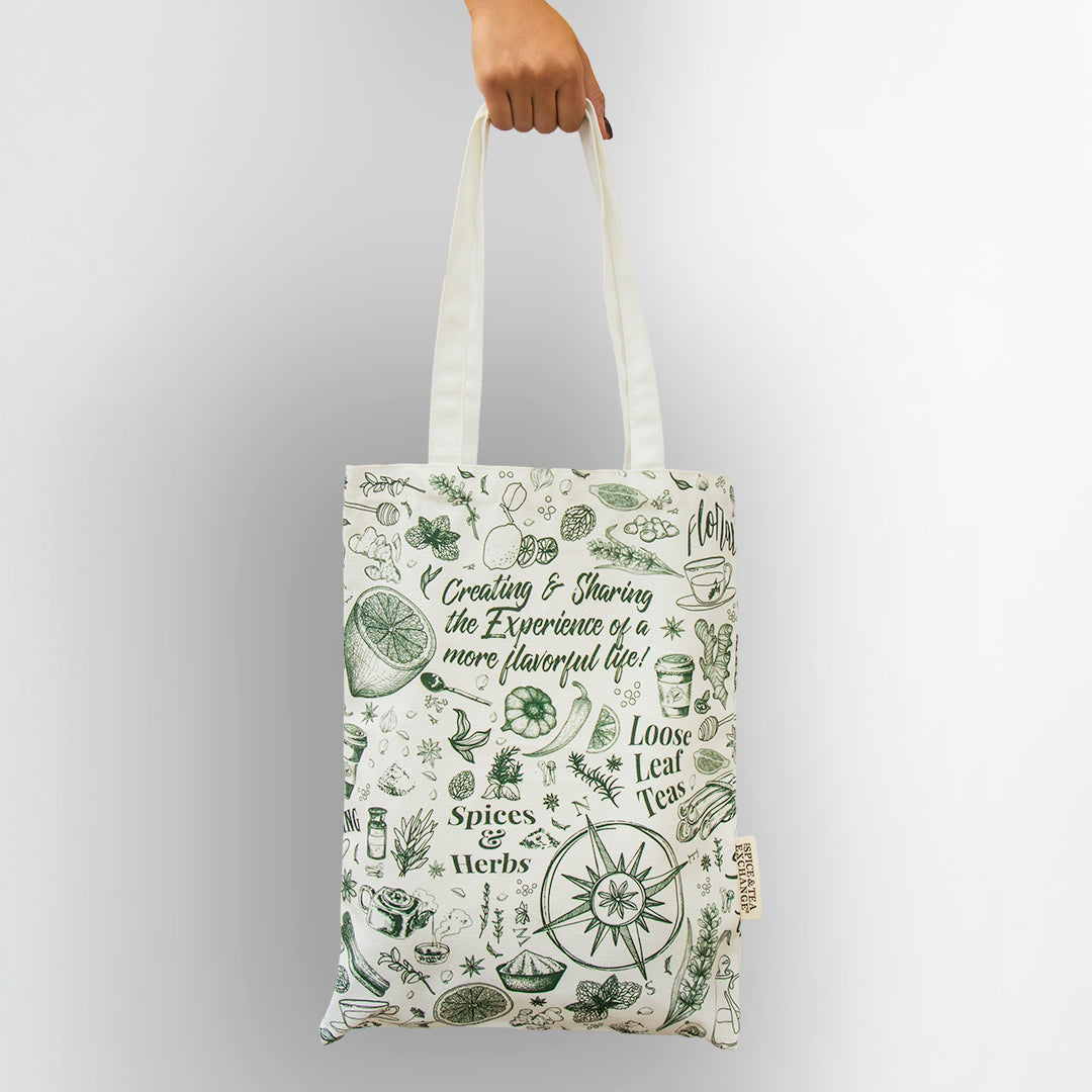 Tote bag with green and white design held by a hand on a light gray background