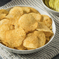 Kettle chips with seasoning on top in white bowl on blue and white striped napkin