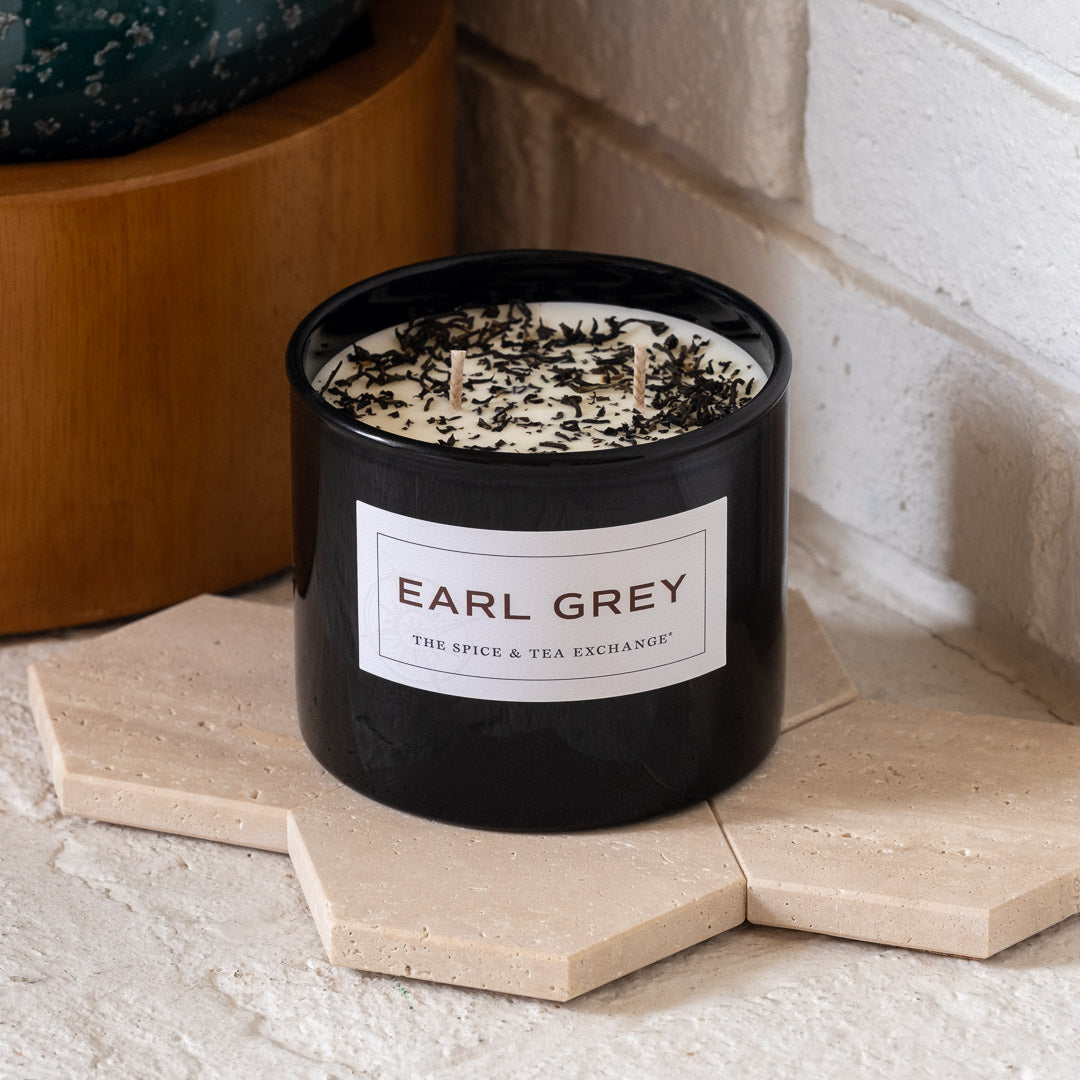 Earl Grey Candle on stone tile holder in front of white brick wall