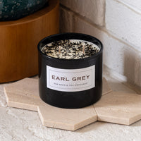 Earl Grey Candle on stone tile holder in front of white brick wall