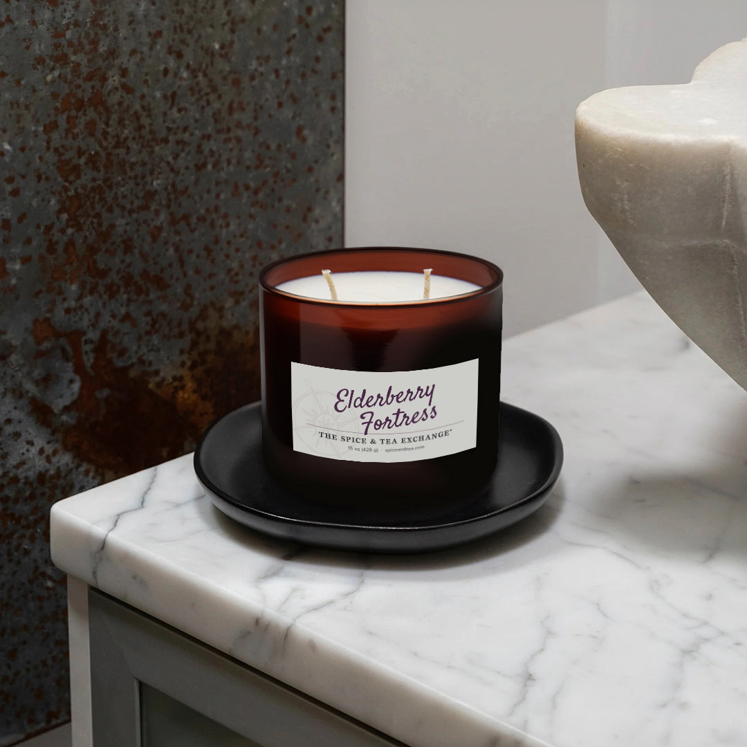 Candle in an amber glass jar with a label on a marble surface
