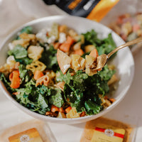 Bowl of salad with a spoonful of salad held above it, with a blurred background.