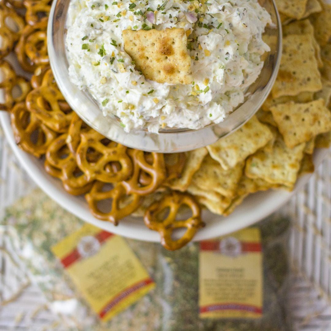 Dip in a bowl with crackers and pretzels on a white plate