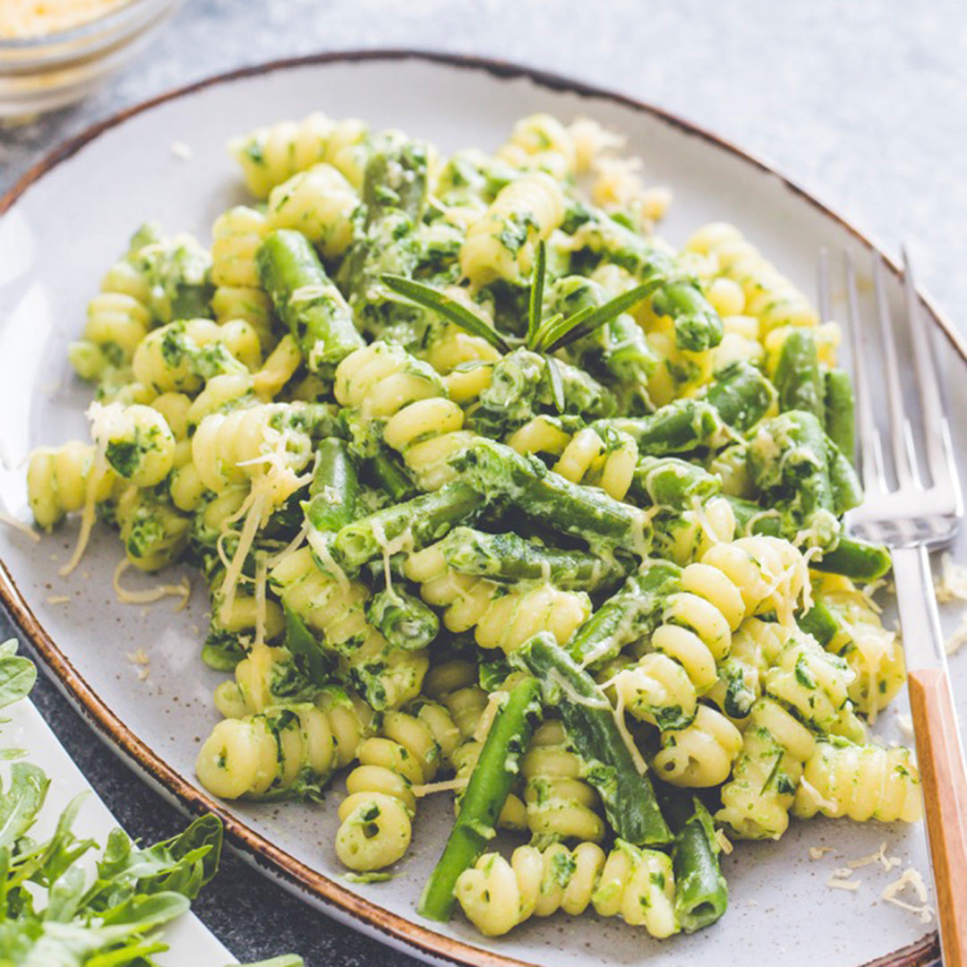 Pasta dish with green vegetables on a plate with a fork