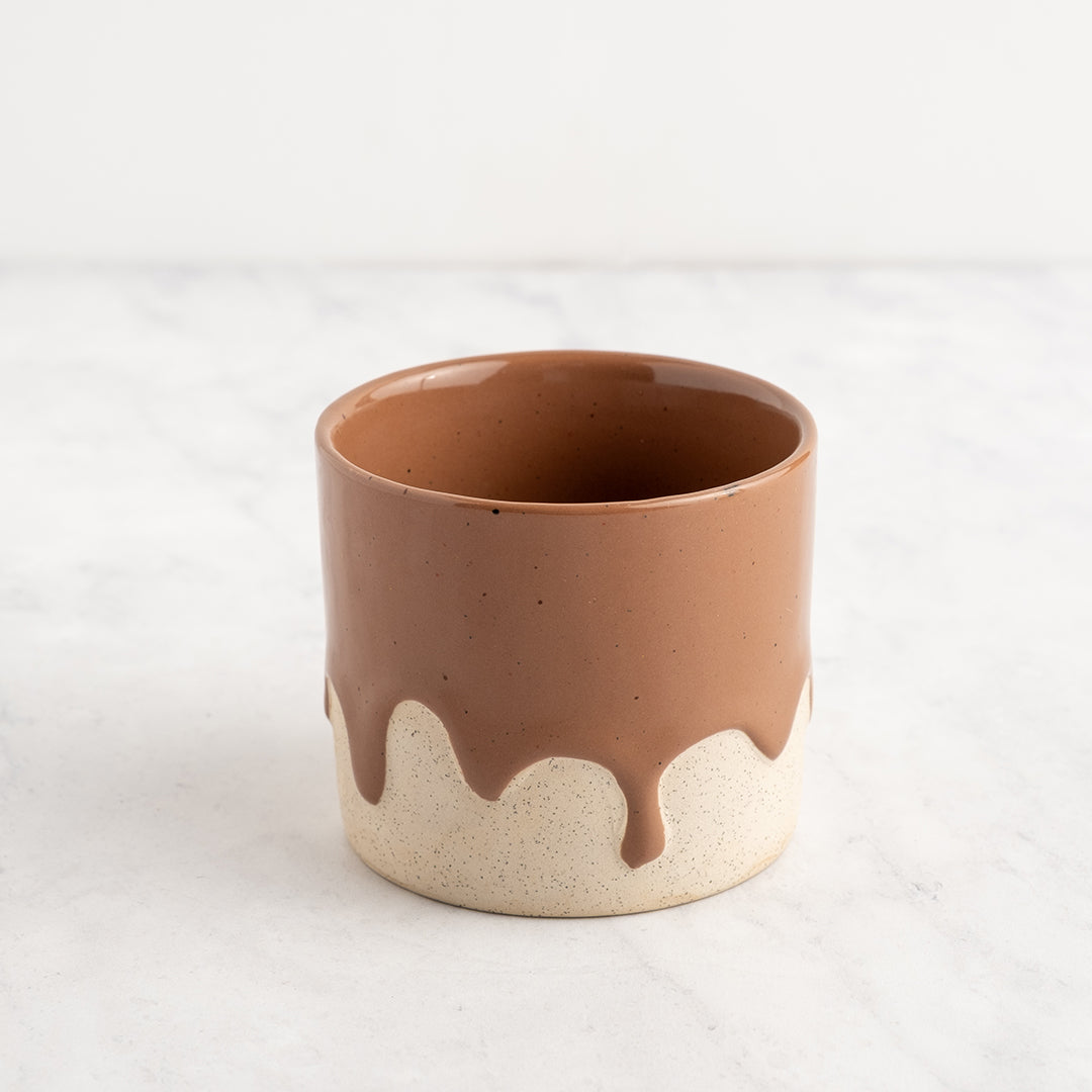 Ceramic cup with brown top and white bottom on a light gray background