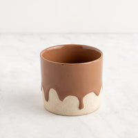 Ceramic cup with brown top and white bottom on a light gray background
