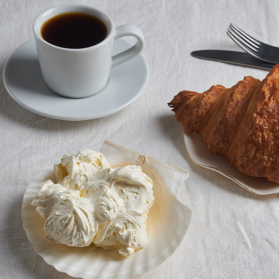 Cup of coffee, croissant, and cream on a white tablecloth