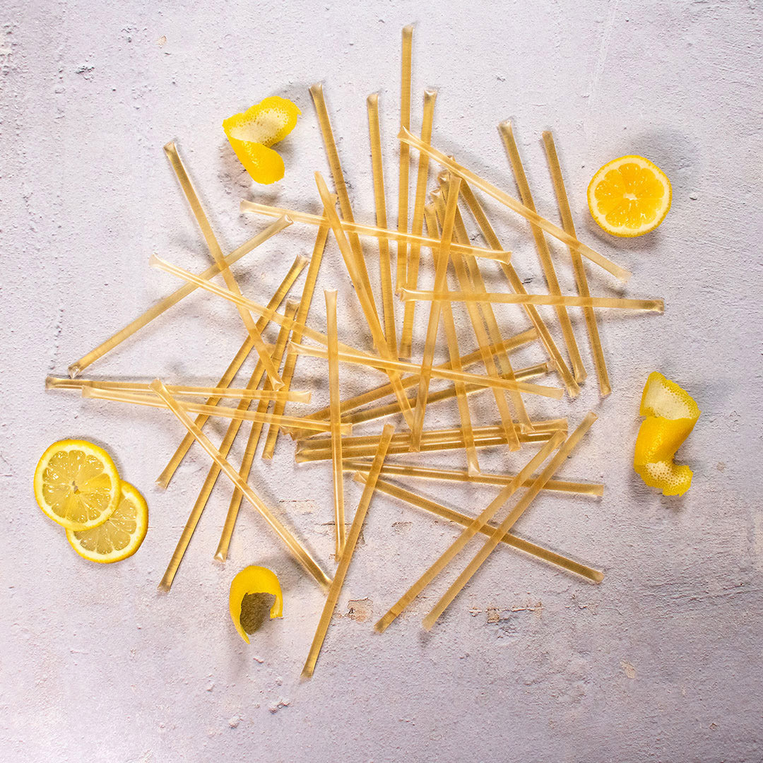Lemon Honey Straws scattered on a light surface with lemon slices and peels—an easy, natural way to add raw honey flavor to your healthy snacks.