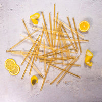 Lemon Honey Straws scattered on a light surface with lemon slices and peels—an easy, natural way to add raw honey flavor to your healthy snacks.