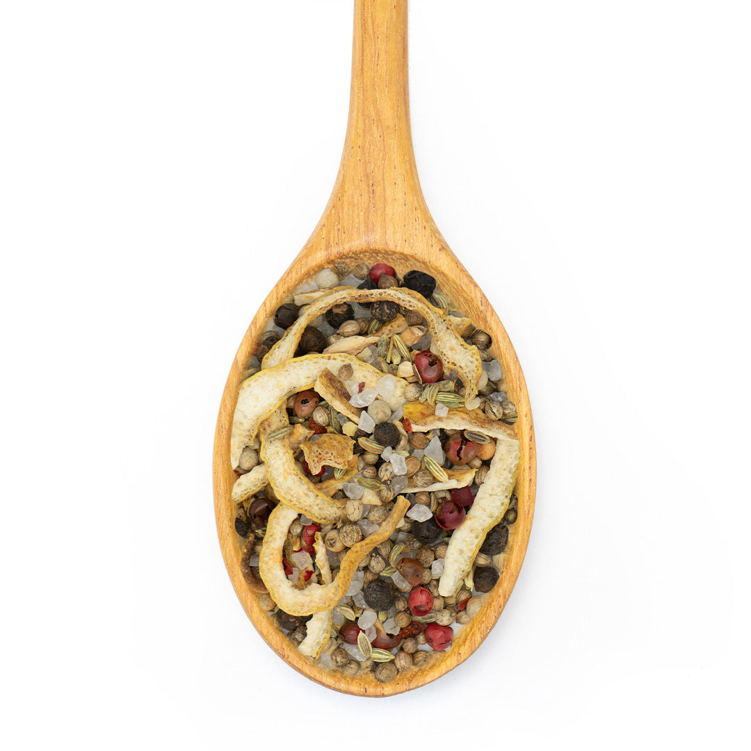 A wooden spoon filled with dried citrus peel strips mixed with small whole spices and lentils, photographed from above on a white background.