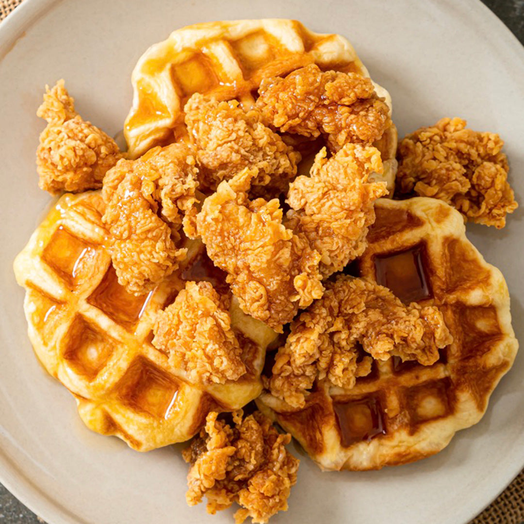 Fried chicken and waffles with syrup on a white plate