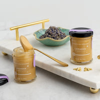 Lavender Whipped Honey Jars on white marble platter with bent honey spoon and next to a bowl of lavender