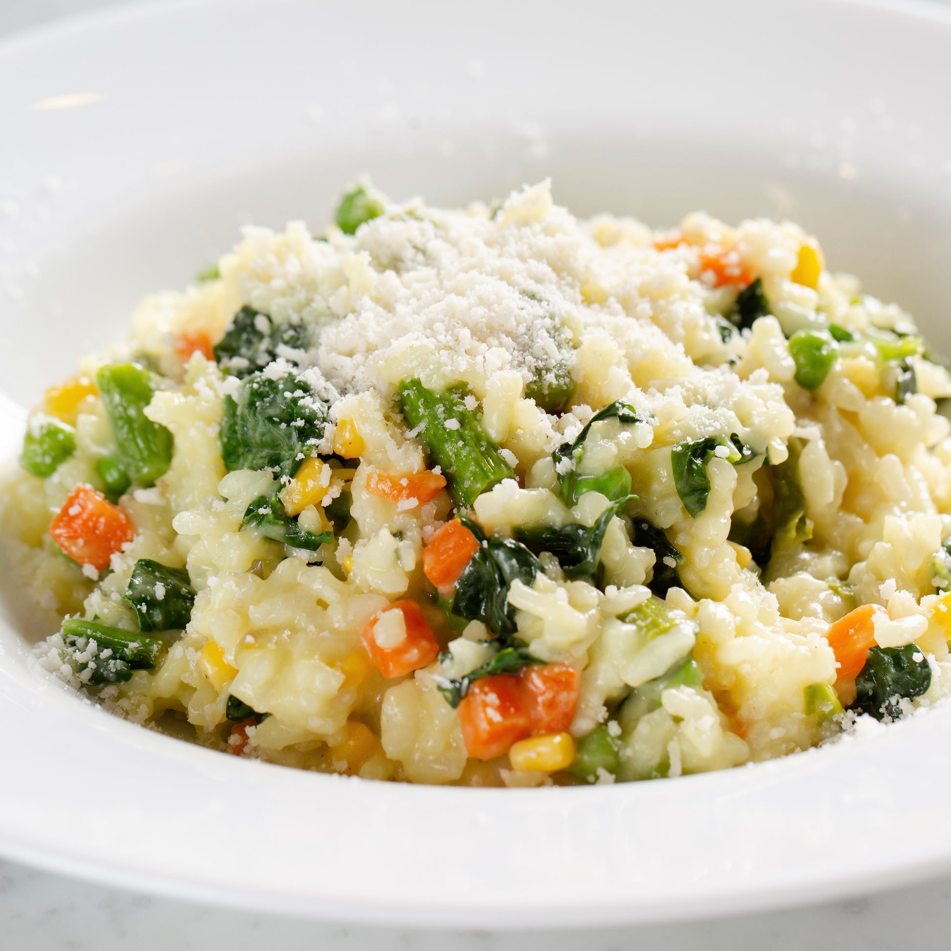 Vegetable risotto with parmesan cheese in a white bowl